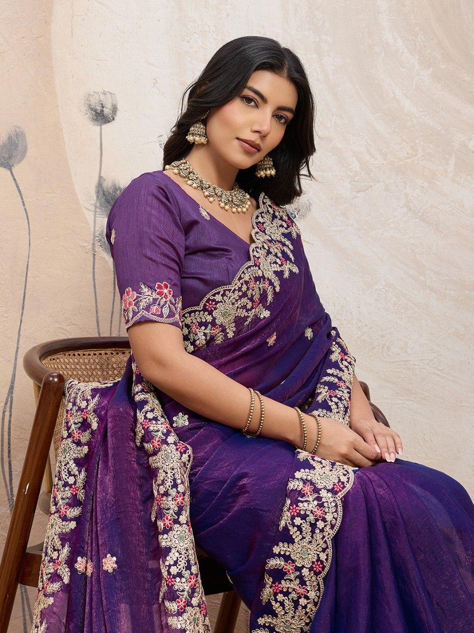 Model sitting gracefully in a purple Disha2 Soft Space Silk Saree with intricate embroidery and cutwork border, styled with traditional jewelry.