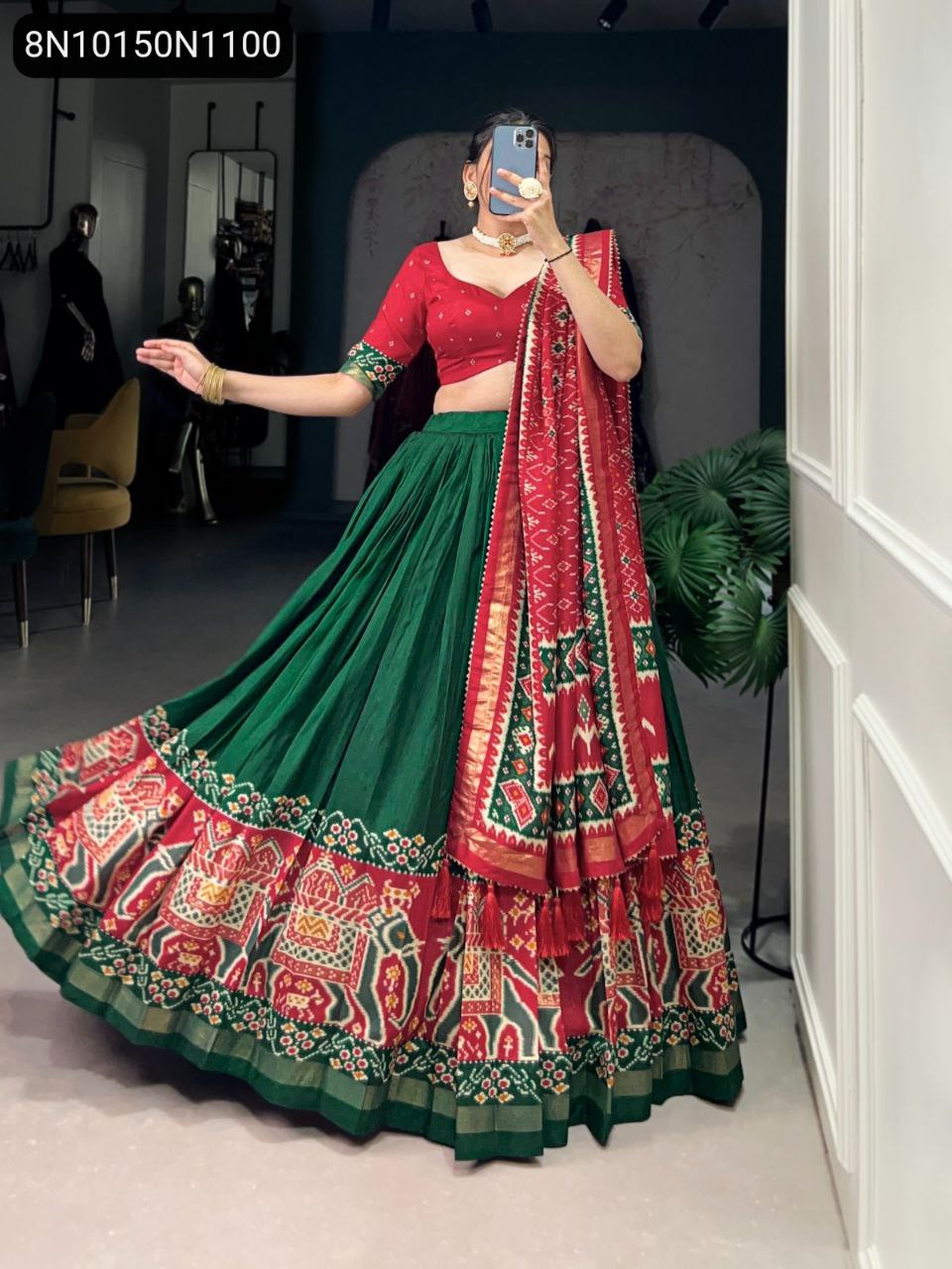 Full body view of model in Green Patola Printed Tasar Silk Lehenga Choli with red dupatta, twirling, front facing.