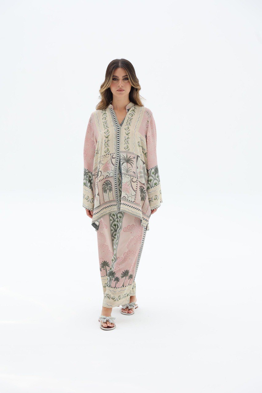 Full shot of woman wearing a pink multi-print satin co-ord set with tropical motifs, standing.