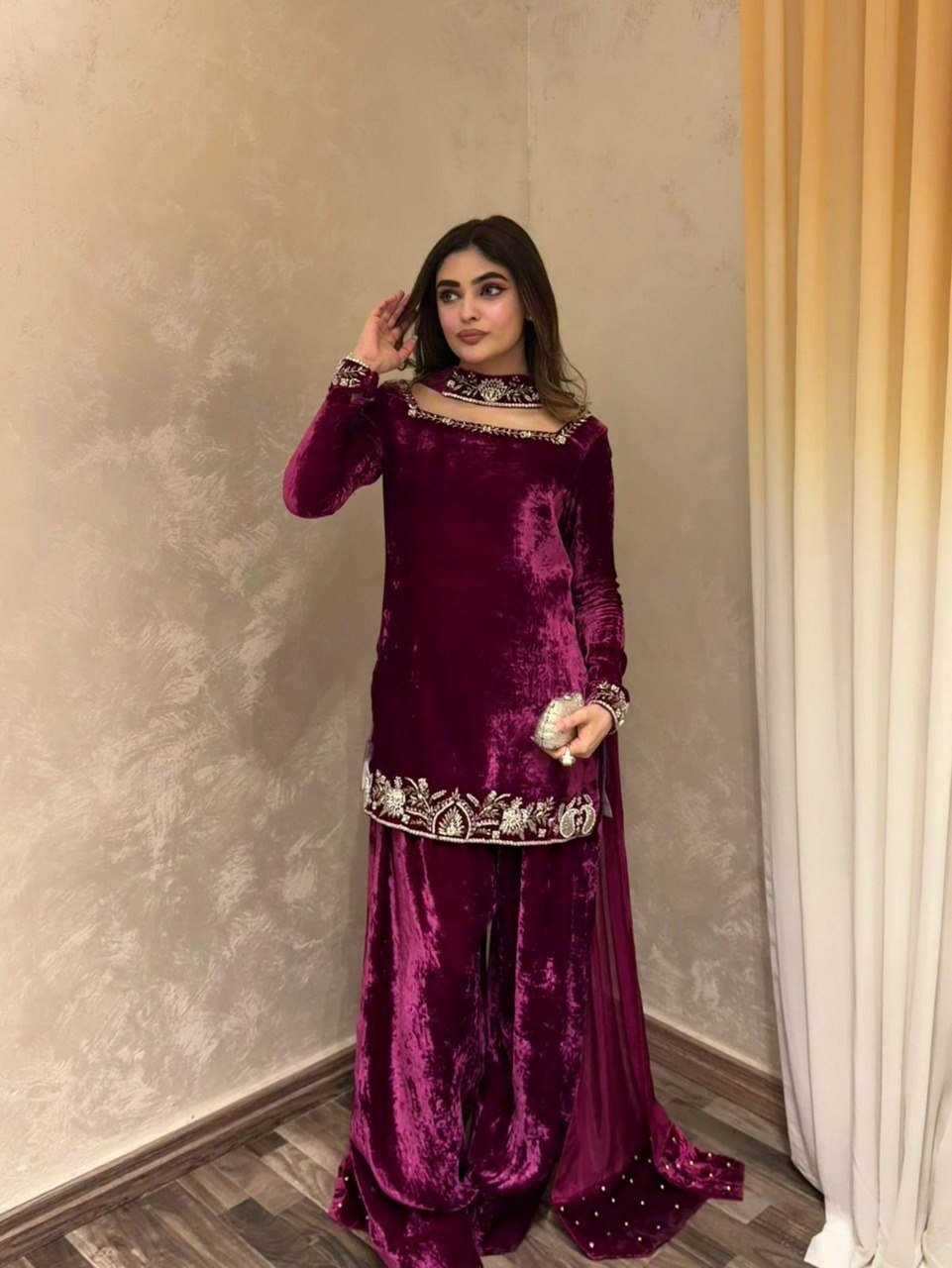 Model posing in a deep wine velvet embroidered sharara set with intricate details and a choker neckline.