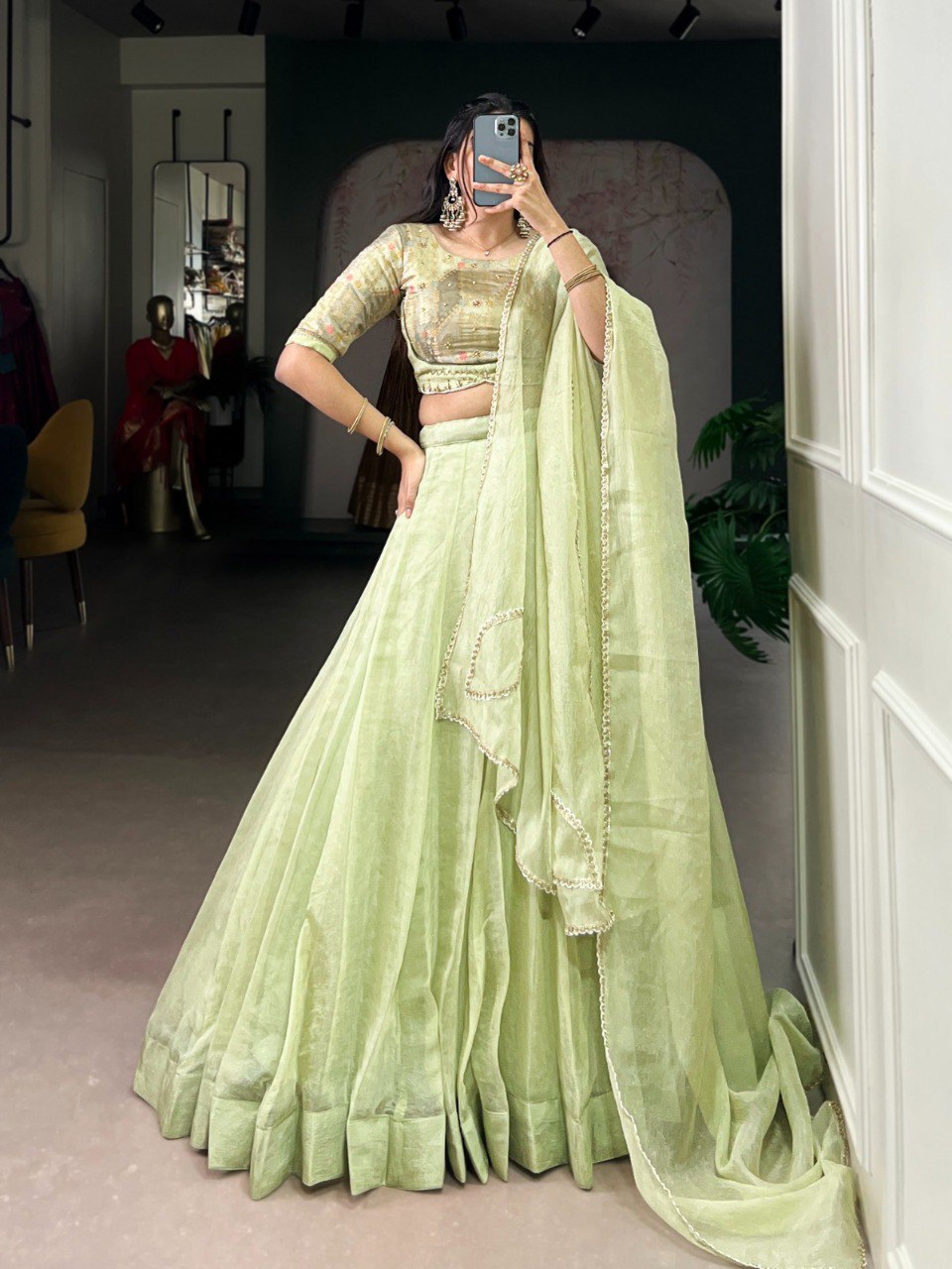 Woman posing elegantly in a pistachio green Allen Crush lehenga with intricate beadwork.