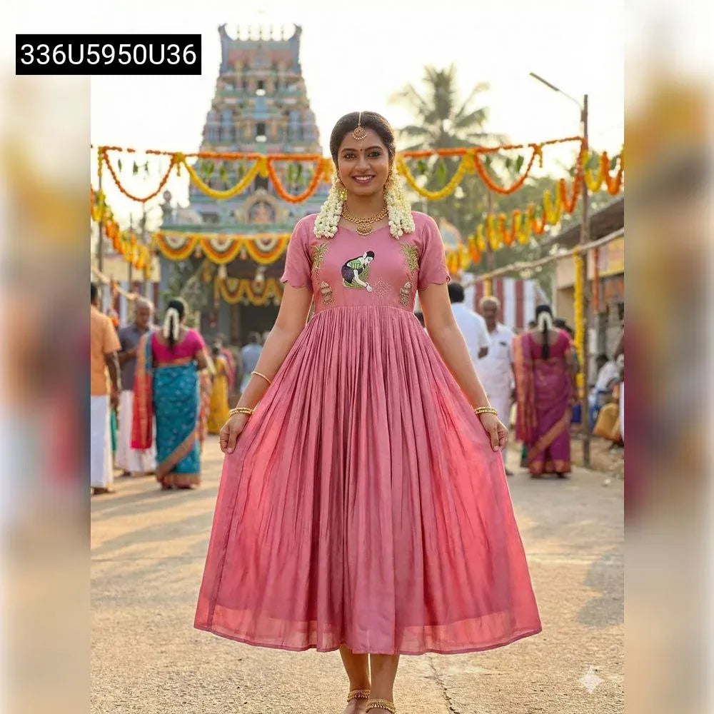 Full body shot of a woman in a Mauve Pink Pongal special gown with embroidery and festive temple background.