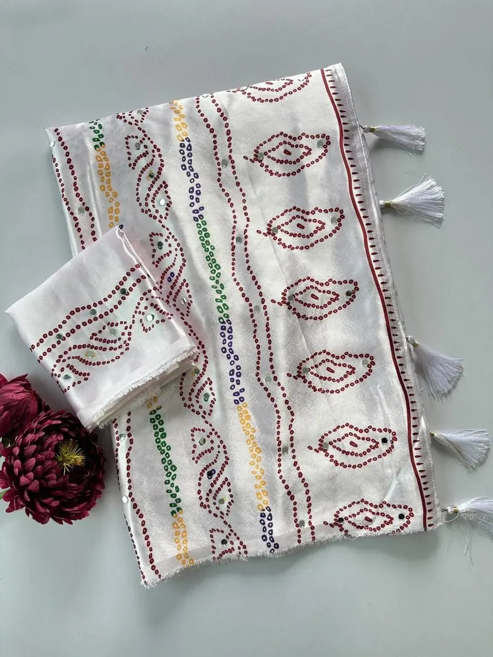 Folded white bandhani saree with multi-color dots and tassels