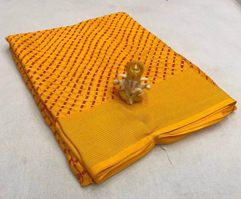 Folded yellow bandhej mothda saree with gold zari border and small Ganesha figurine