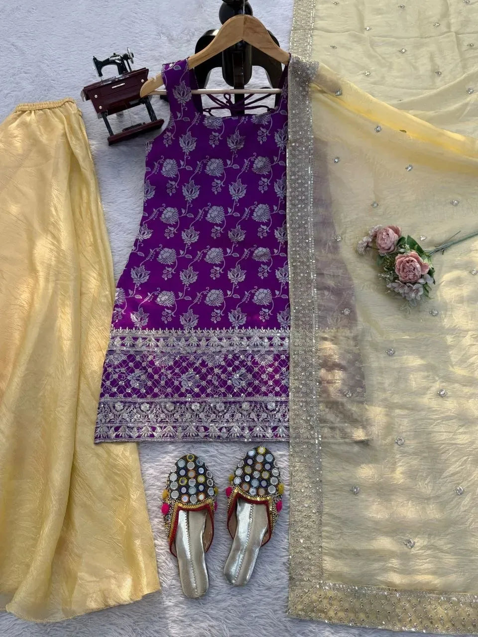 Flat lay of purple jacquard kurti set with yellow plazo, dupatta and juttis