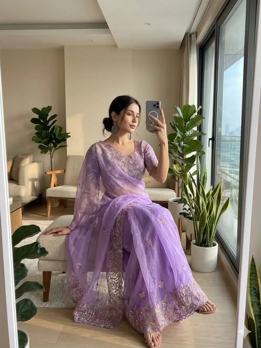 Model sitting wearing lavender chiffon saree with detailed embroidery