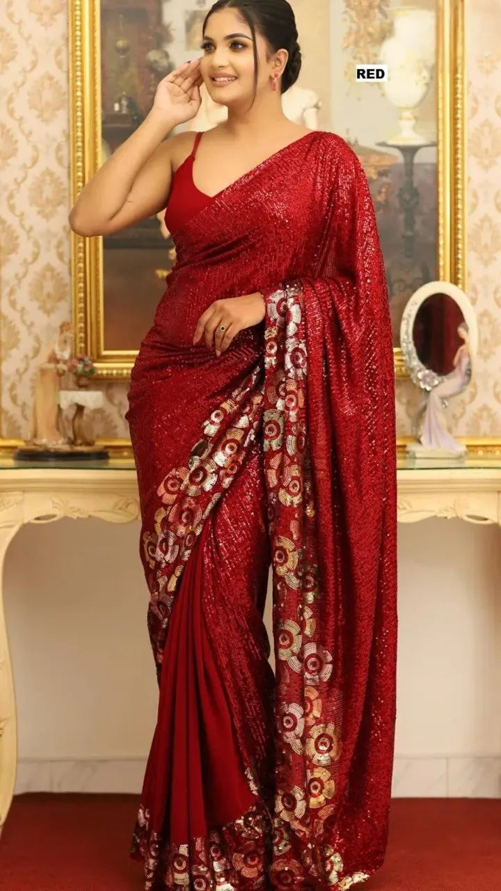Woman posing in a red georgette saree with heavy sequin work and floral border