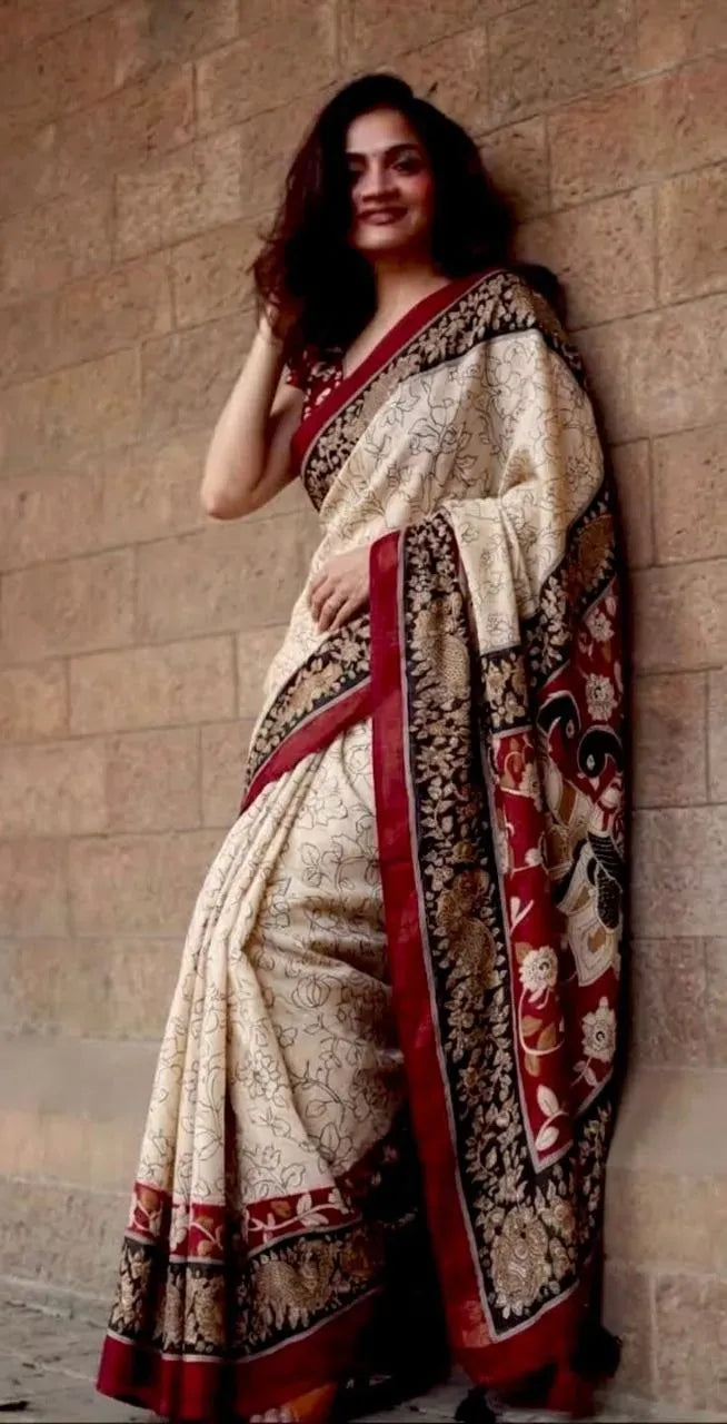 Model wearing cream and red georgette saree leaning against a brick wall