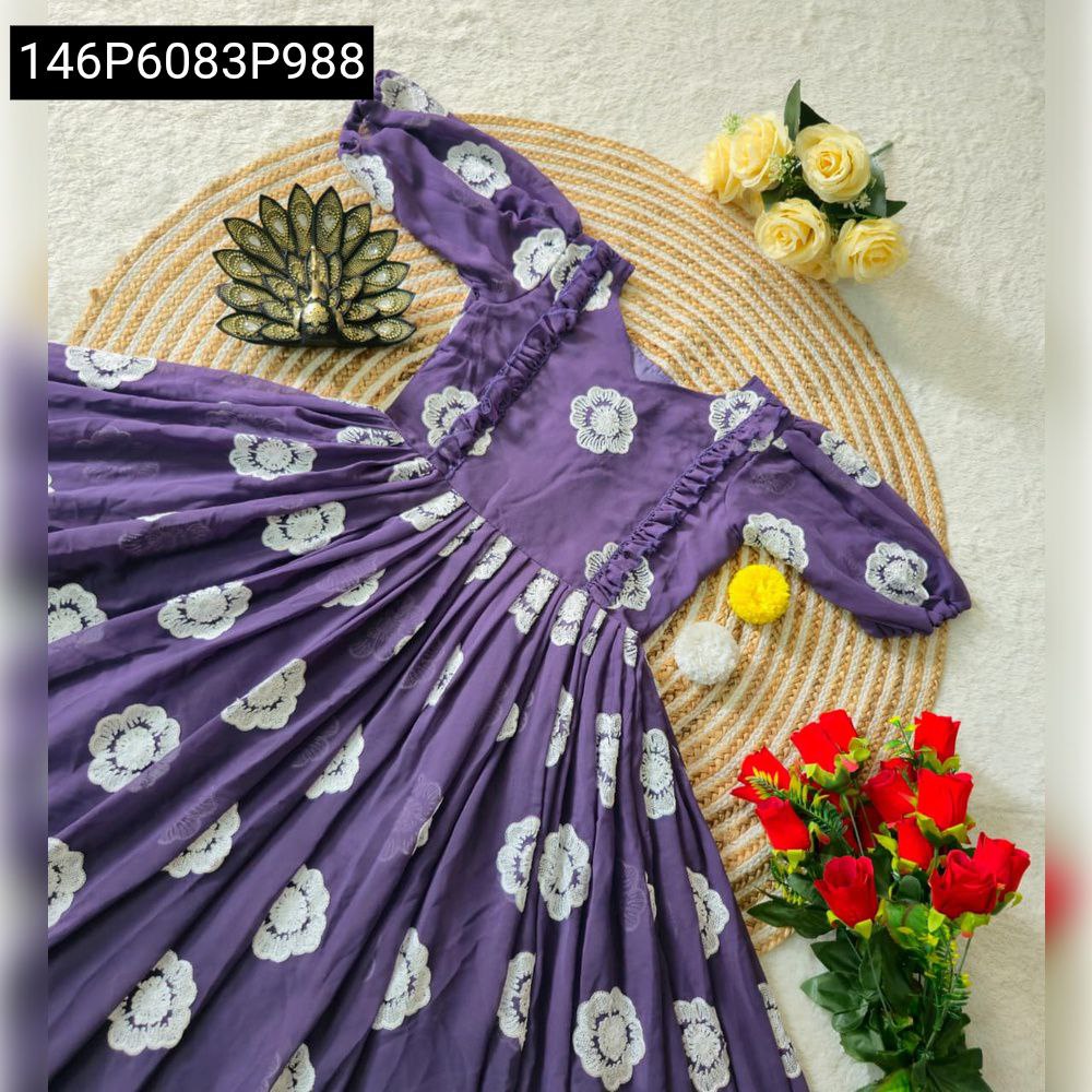 Flat lay of lavender georgette gown with white thread work floral patterns, adorned with red and yellow flowers.