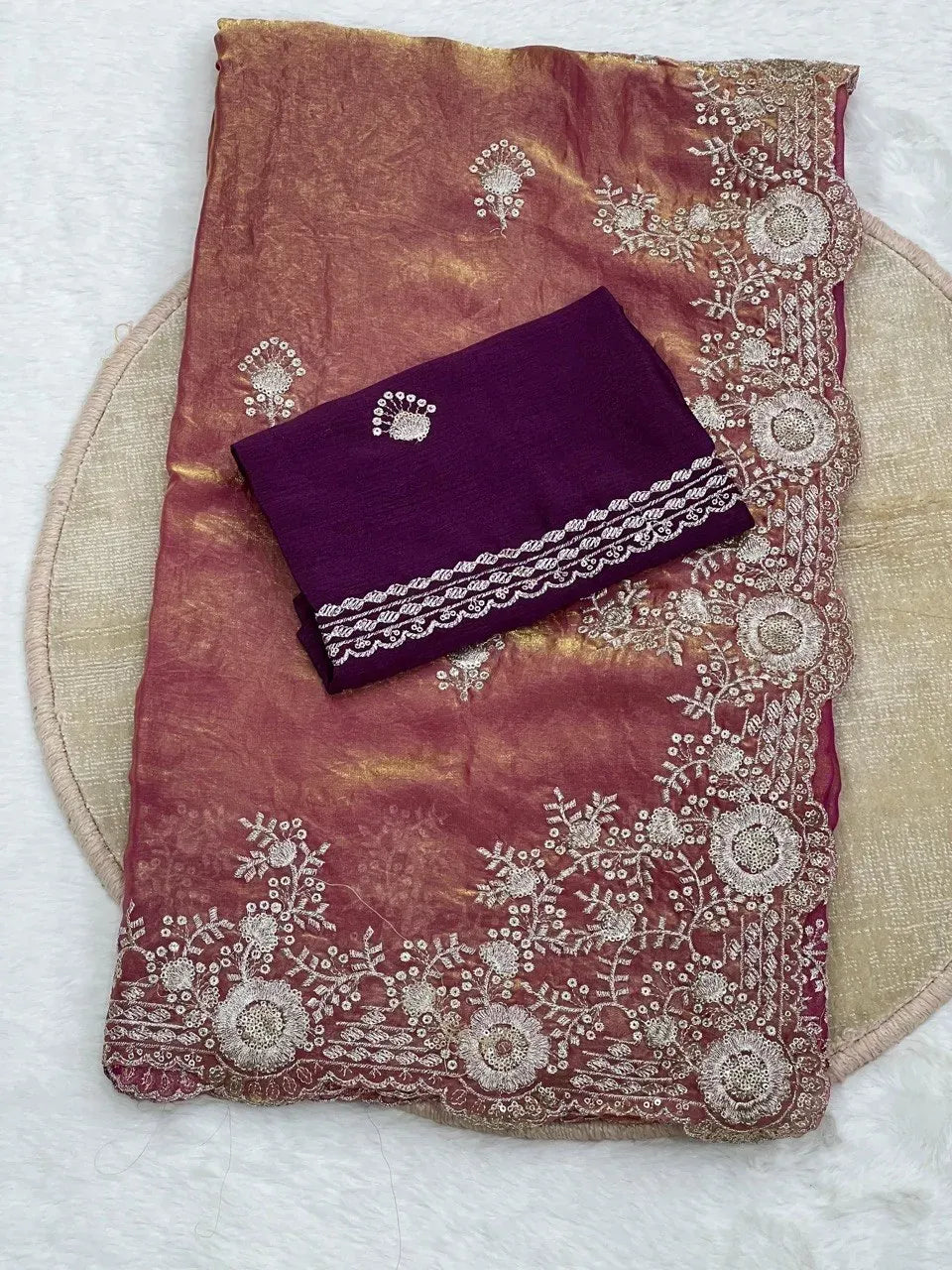 Burgundy space silk saree folded with purple Chinon silk blouse on a circular mat