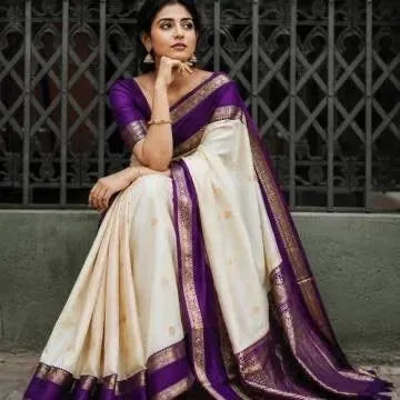 Model sitting wearing cream and purple kanjivaram soft silk saree with rich zari border