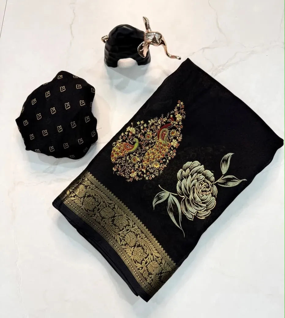 Folded black silk saree with intricate gold border and matching blouse piece next to an elephant decor