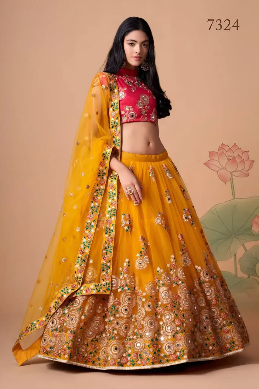 Model wearing mustard yellow mirror work net lehenga with rani pink blouse and dupatta