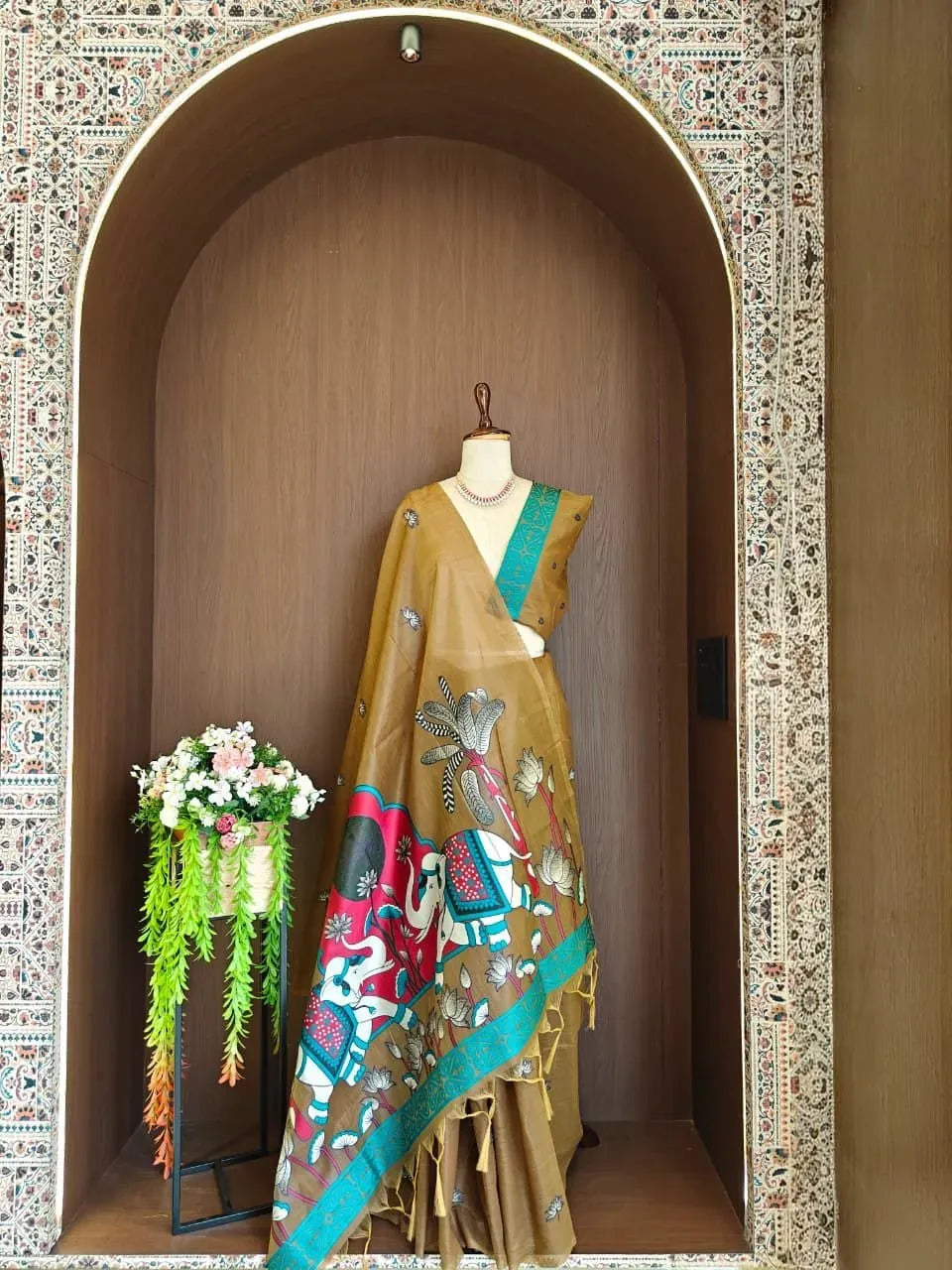 Golden brown muga cotton saree with elephant and lotus weaving on mannequin