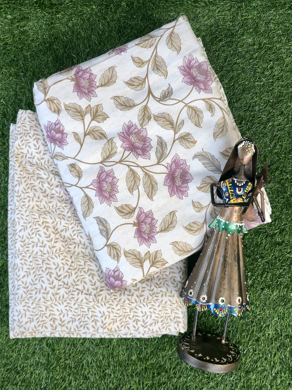 Folded pink floral print pure cotton single dohar with decorative figurine on grass