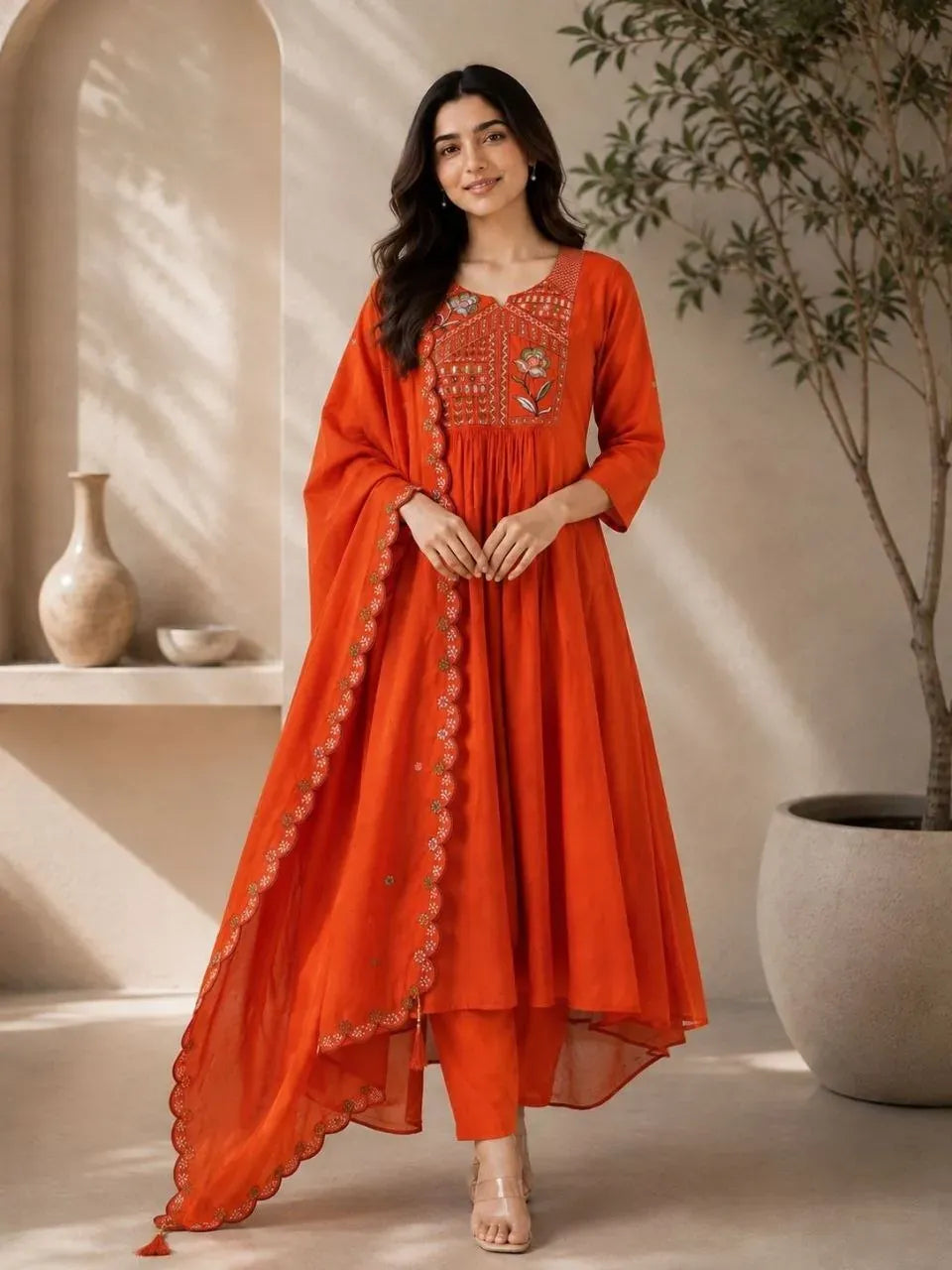 Model wearing bright orange silk kurti and palazzo set with embroidered dupatta