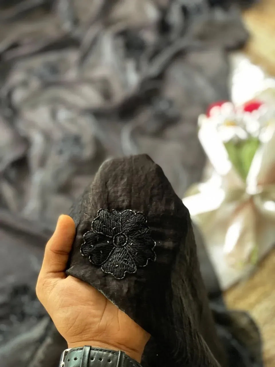 Hand holding black space silk fabric with floral beadwork