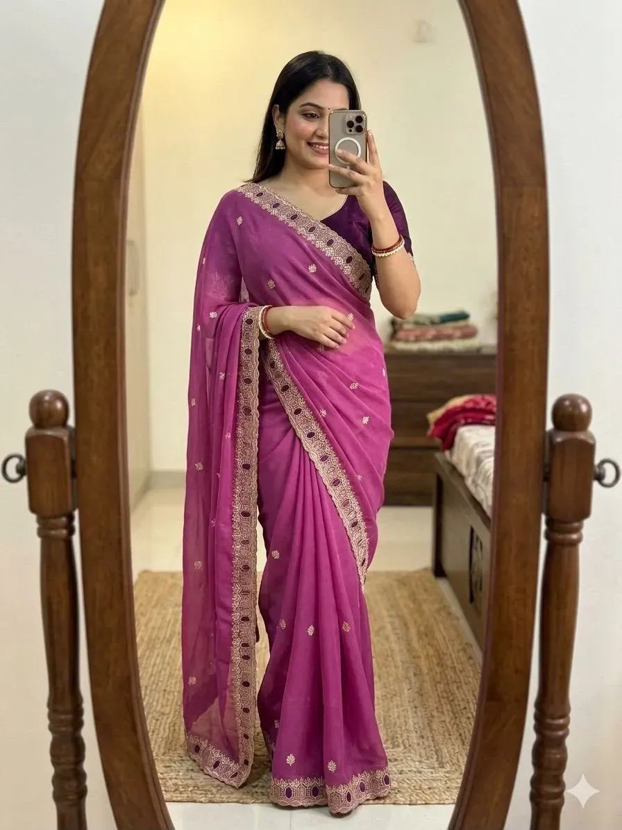 Model wearing pink georgette embroidered saree standing in front of mirror
