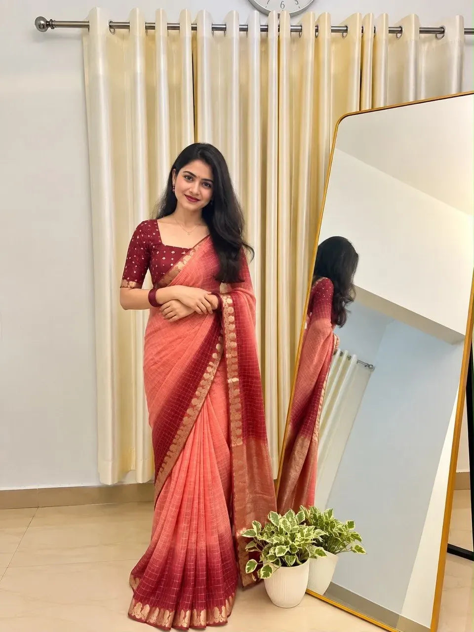 Model wearing peach and maroon ombre georgette saree standing in front of mirror