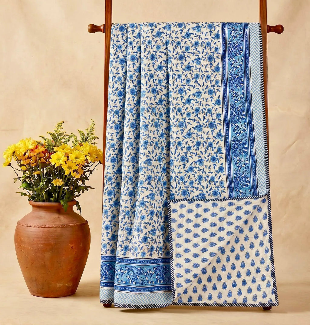 Blue and white floral hand block printed cotton double dohar hanging on wooden rack with flower vase