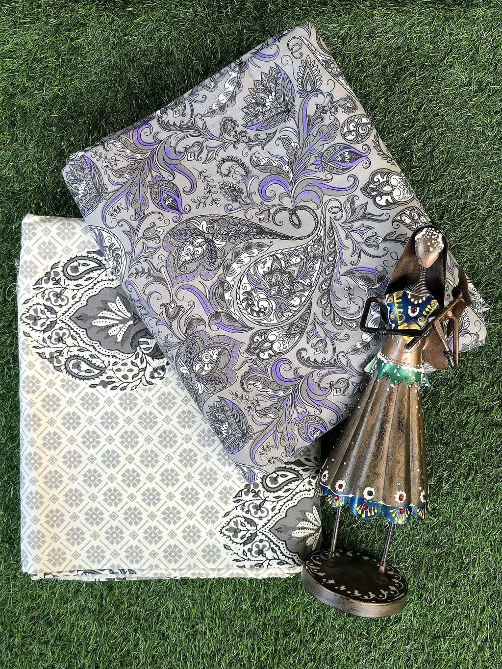 Grey and purple paisley print pure cotton single bed dohar folded on green grass