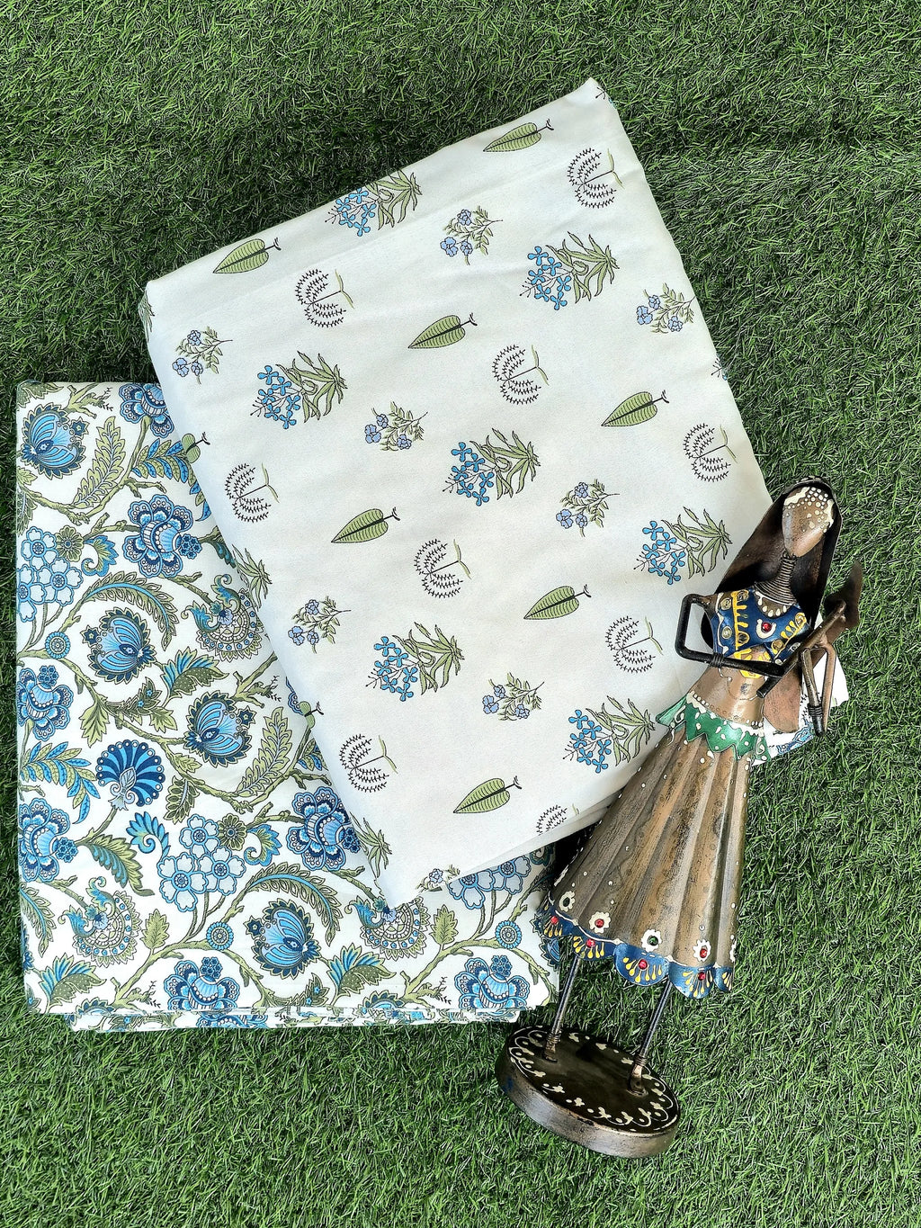 Folded white and blue botanical print cotton dohar pair on grass