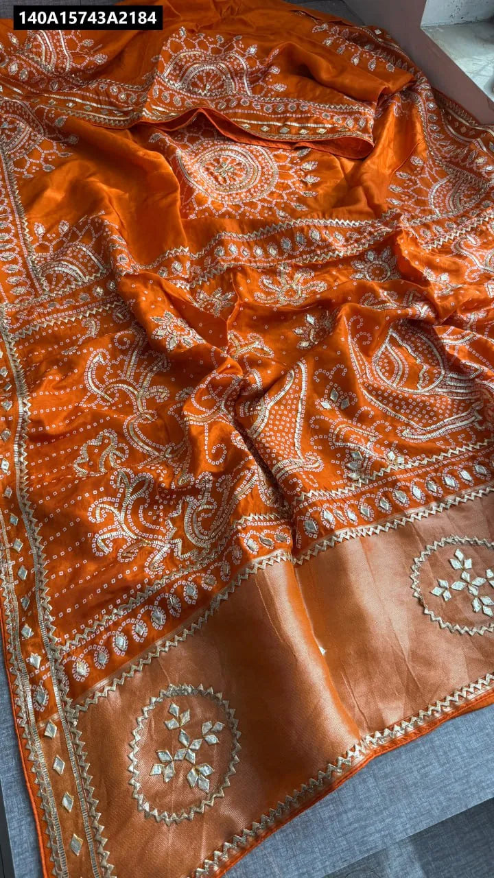 Vibrant Orange Pure Gaji Silk Bandhej Saree with intricate Ek Dani Bandhani and mirror-like embroidery, flat lay view.