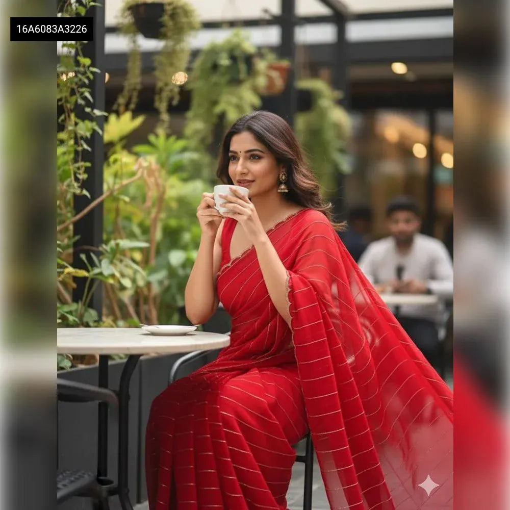 Fashionable woman wearing a stunning pure red georgette saree with handwork, posing elegantly at a cafe with a serene smile.