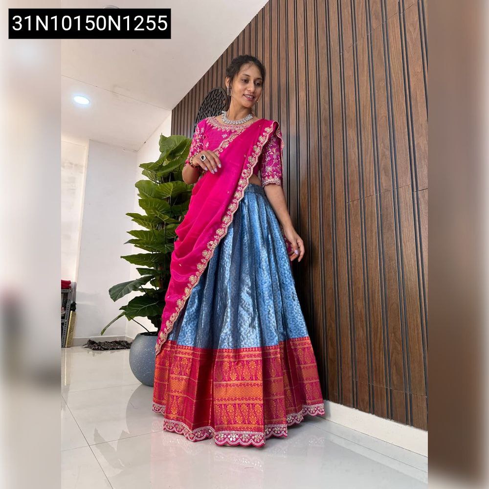 Woman posing elegantly in a pink blouse, blue lehenga with a draped pink voni, front view