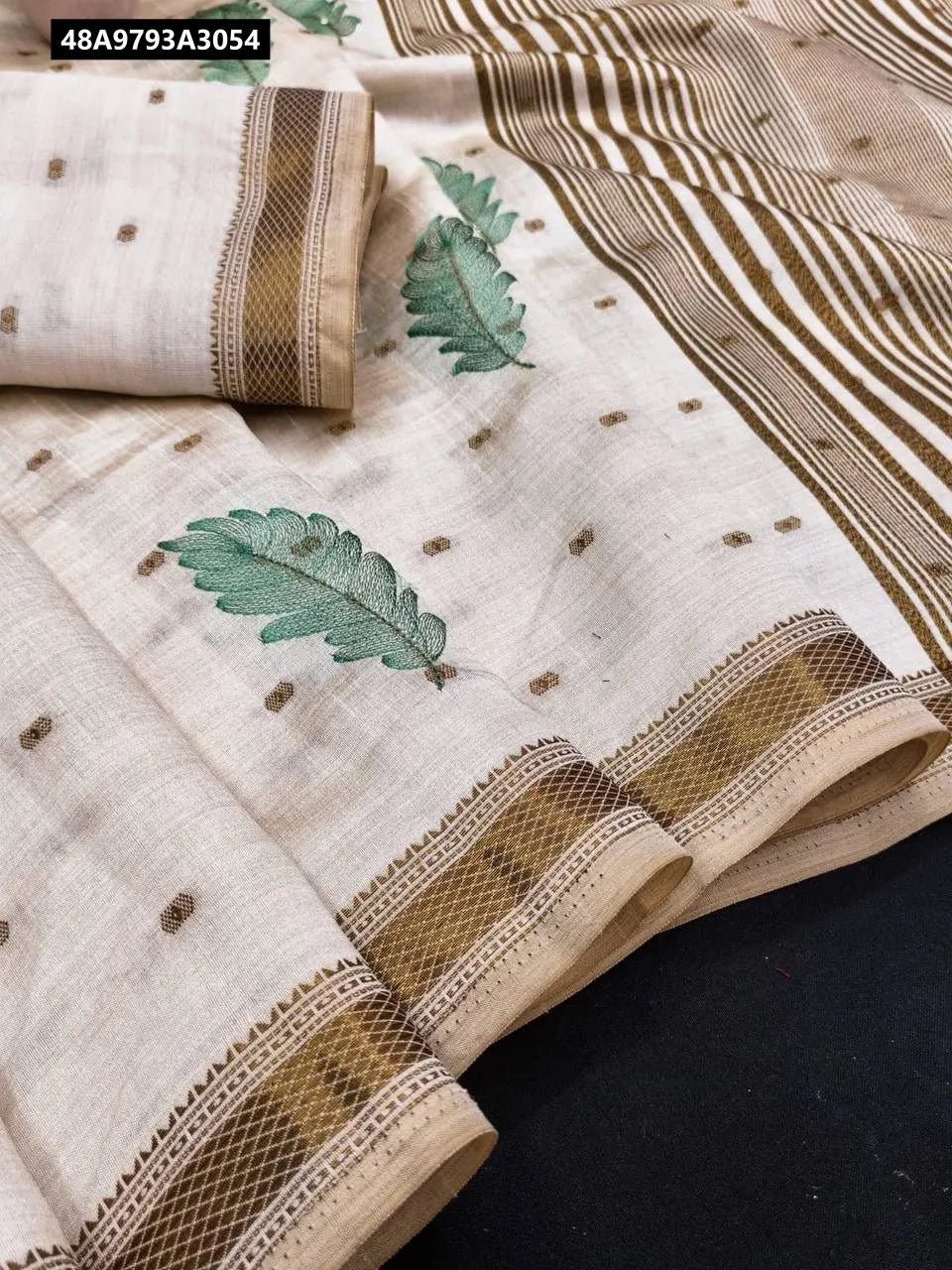Close-up of Pure Tussar Saree with green multi-thread leaf embroidery and contrast border, flat lay.