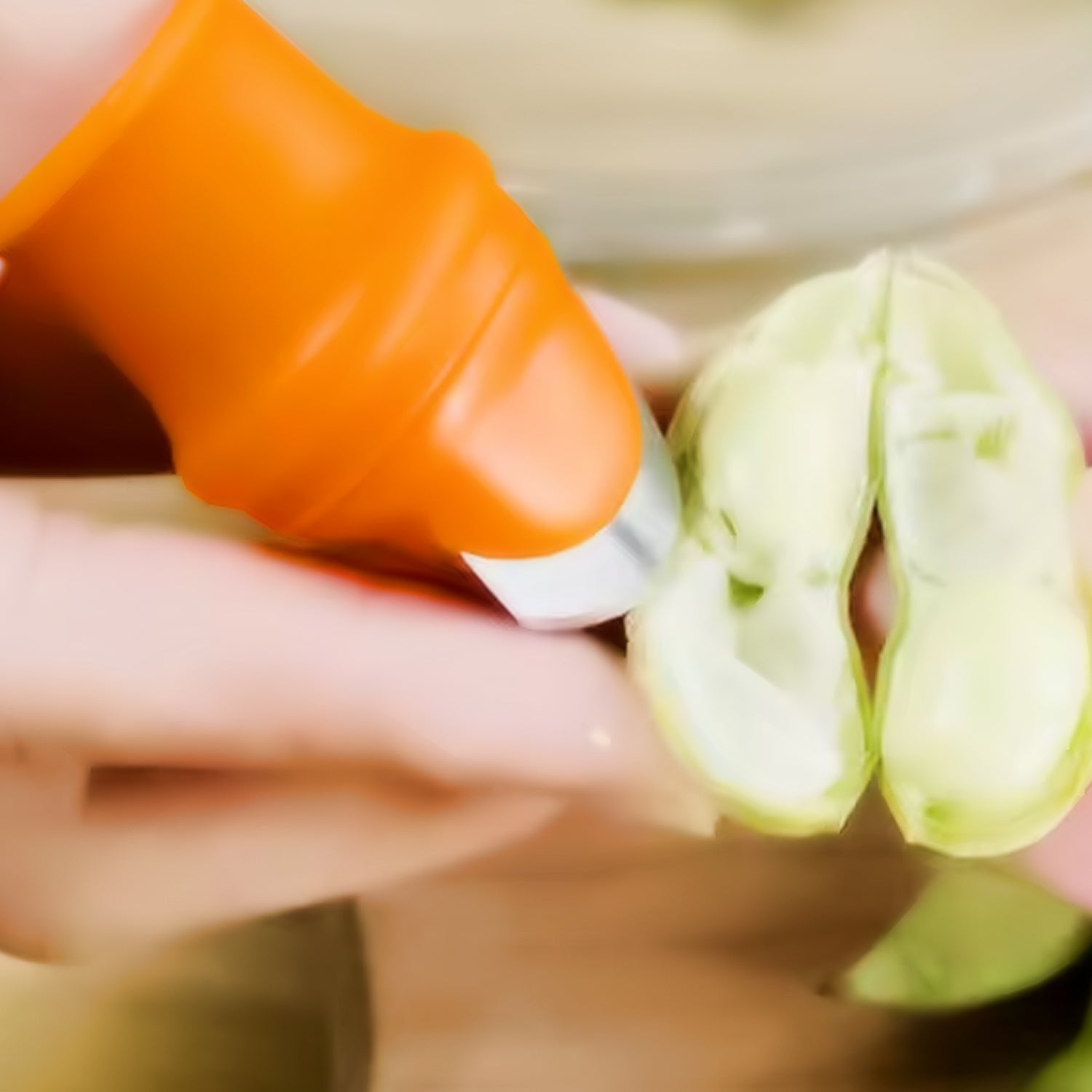 Thumb knife cutter with an orange silicone finger guard, worn on a thumb.