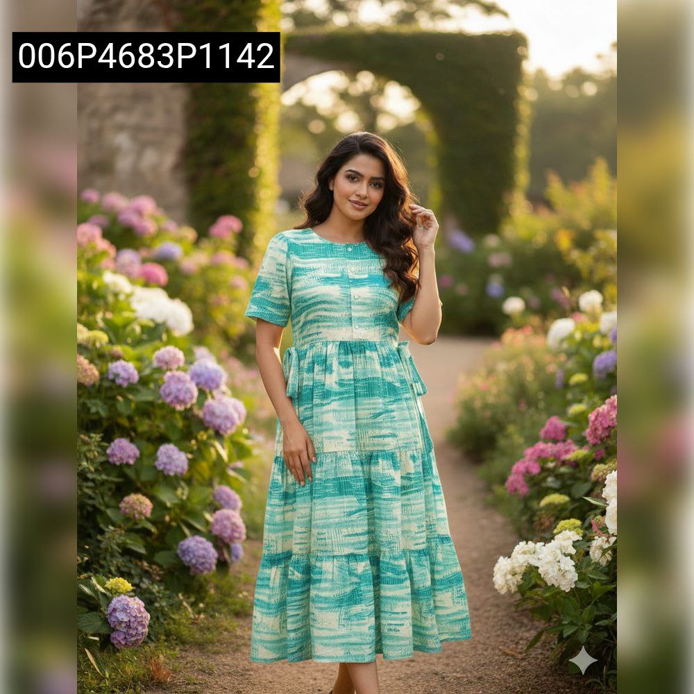 Model wearing an Ocean Wave Teal Rayon foil print tiered maxi dress in a lush garden setting, smiling.