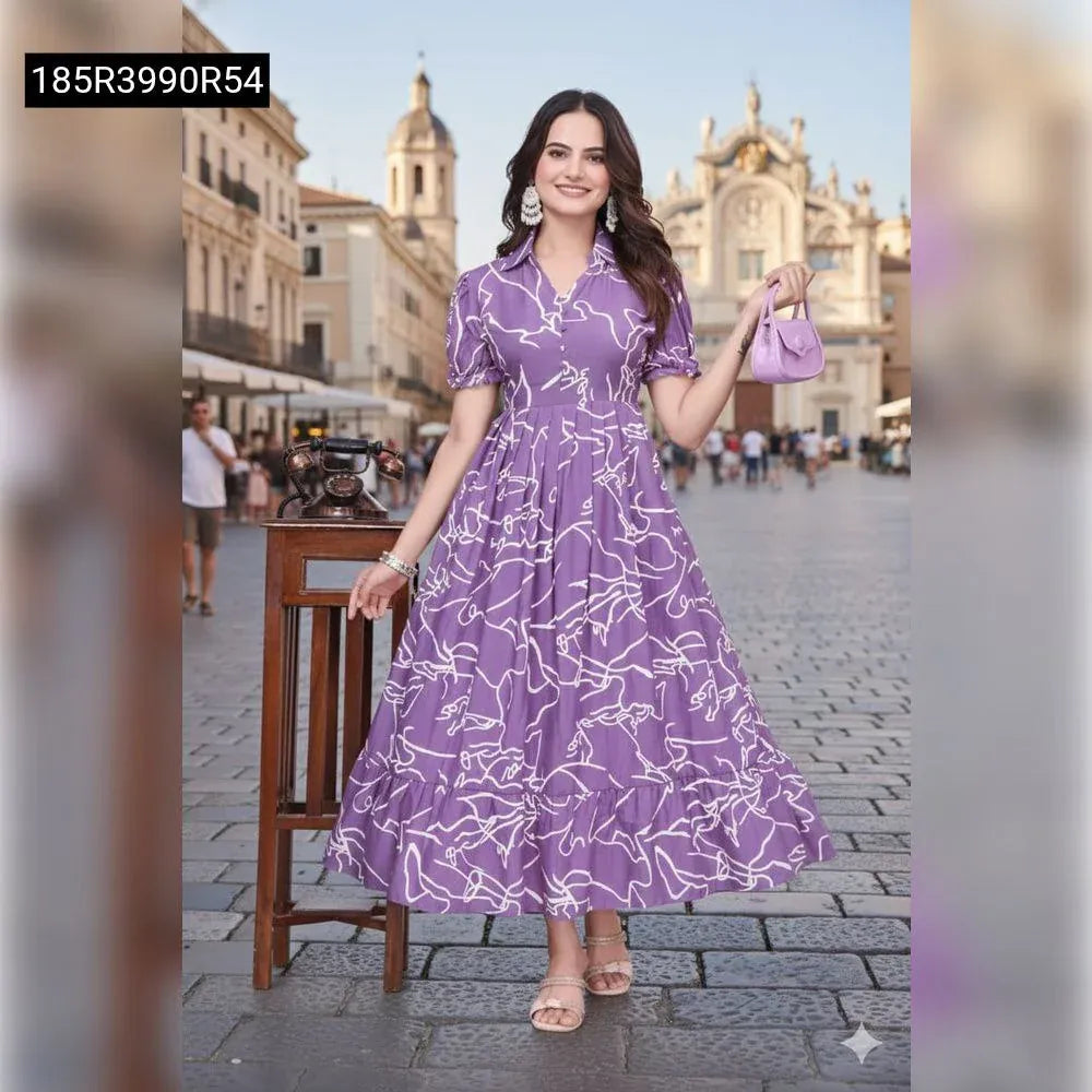 Smiling female model wearing a lavender rayon printed flared midi dress with abstract white patterns, holding a matching small handbag, standing outdoors in a European city setting. Full body, front view.