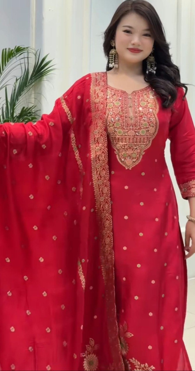 Model posing in the red Banarasi suit set, emphasizing the full ensemble and festive appeal, smiling at the camera.