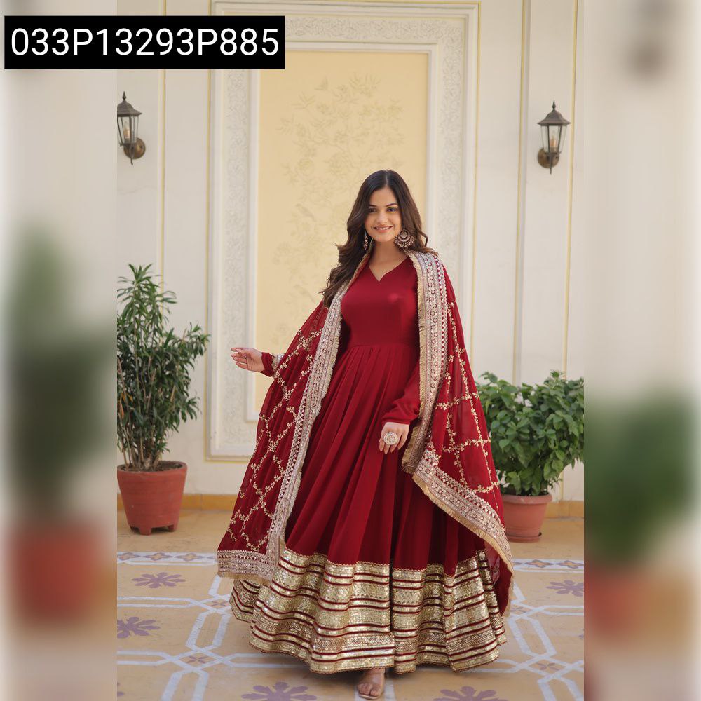Full body shot of a woman in a maroon embroidered anarkali gown, smiling, with a decorative background.