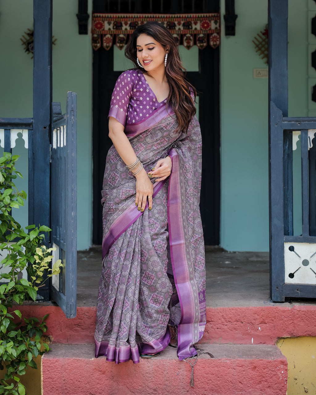 Full body shot of a woman in a regal purple pure linen saree, standing gracefully on steps, showcasing the traditional motifs and design.