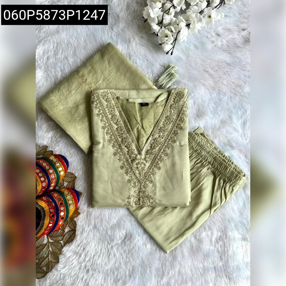 Flat lay of light green Roman silk kurti set with embroidery and sequence work, folded, with matching pant, dupatta, and traditional accessories.