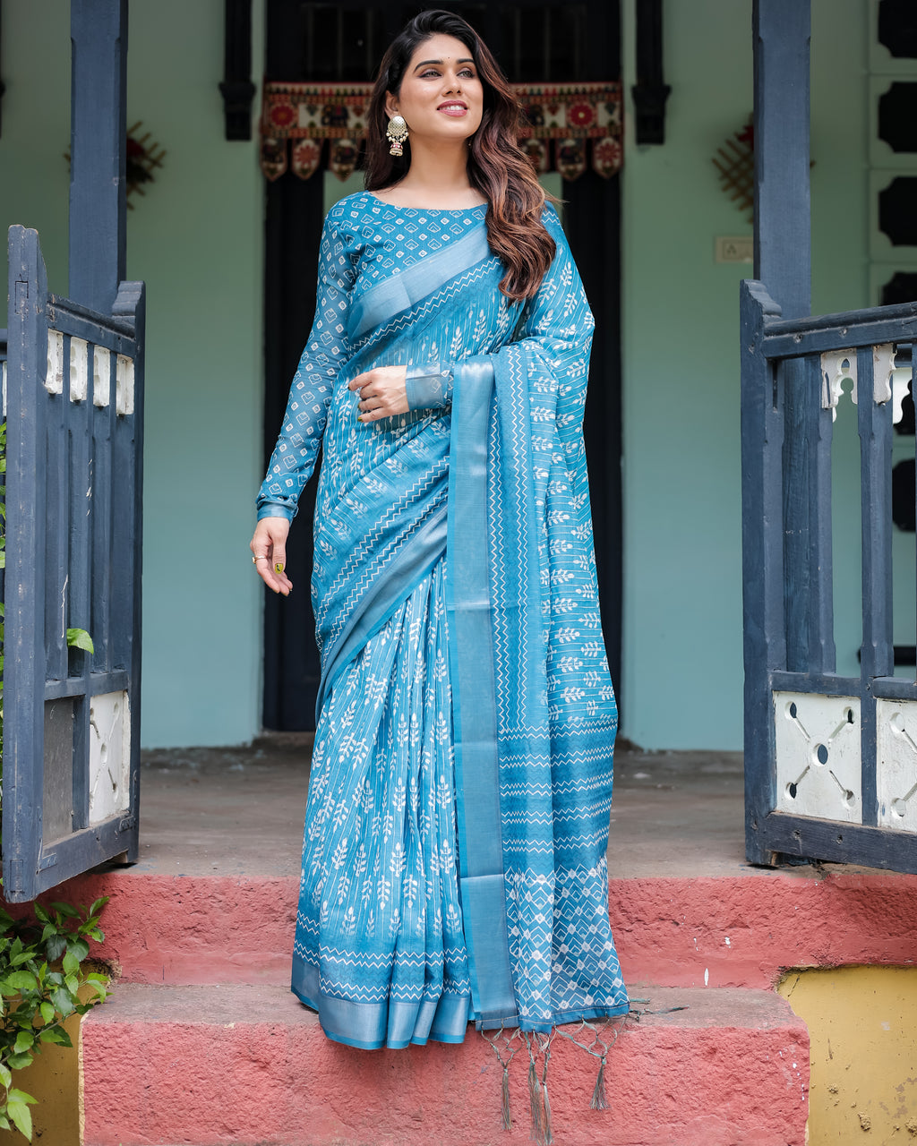 Elegant Women's Turquoise Blue Linen Saree with Bandhani prints and tassels, worn by a model in a traditional setting.