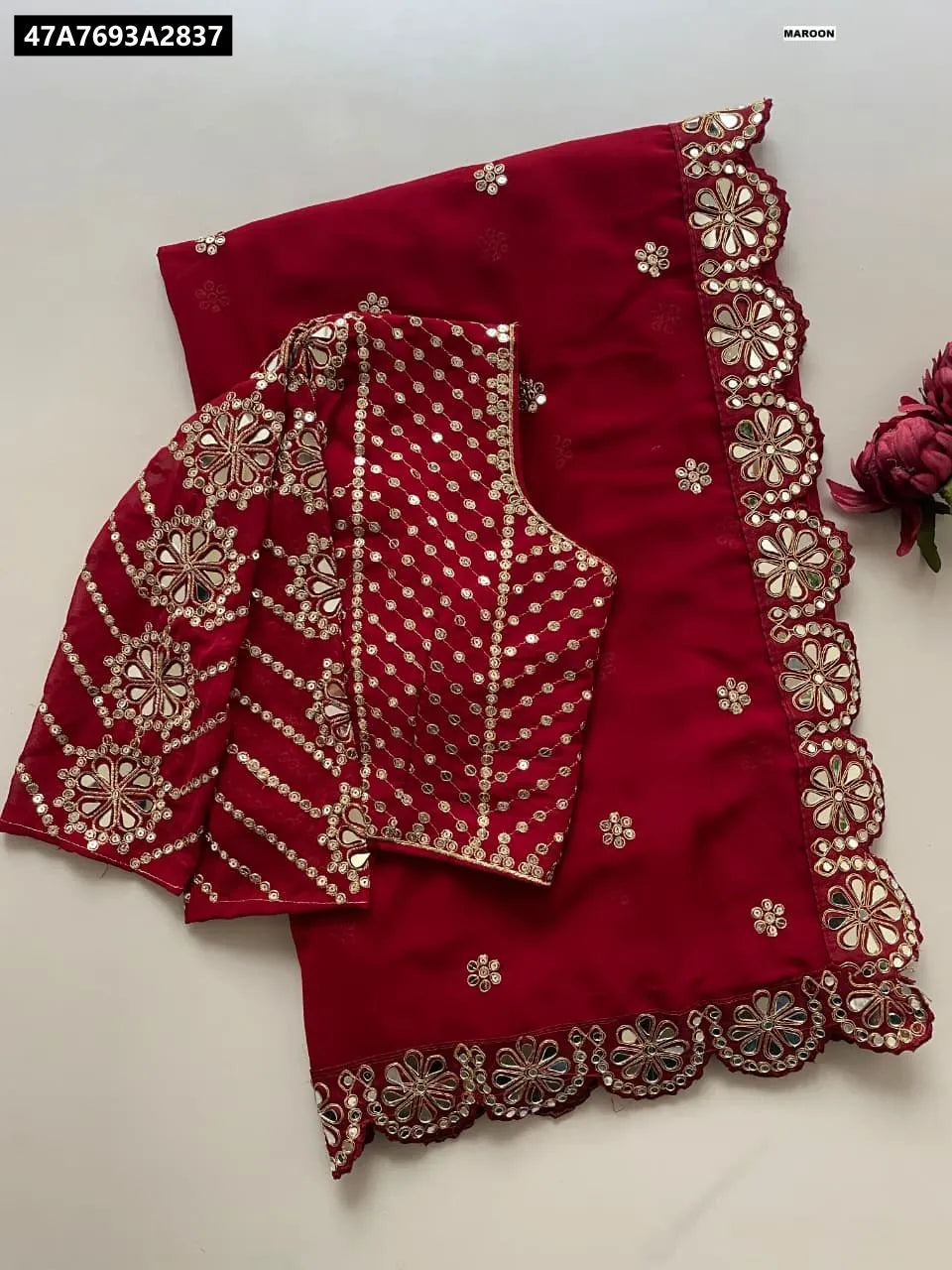 Maroon Faux Georgette Saree with sequence and mirror work and matching embroidered blouse, flat lay.