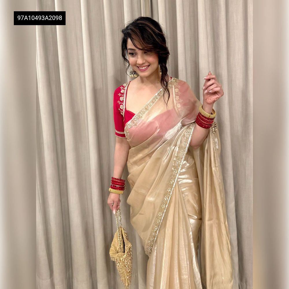 Smiling model wearing TRENDBUY Champagne Gold Zimichu Saree with red blouse, showing full ensemble and party look