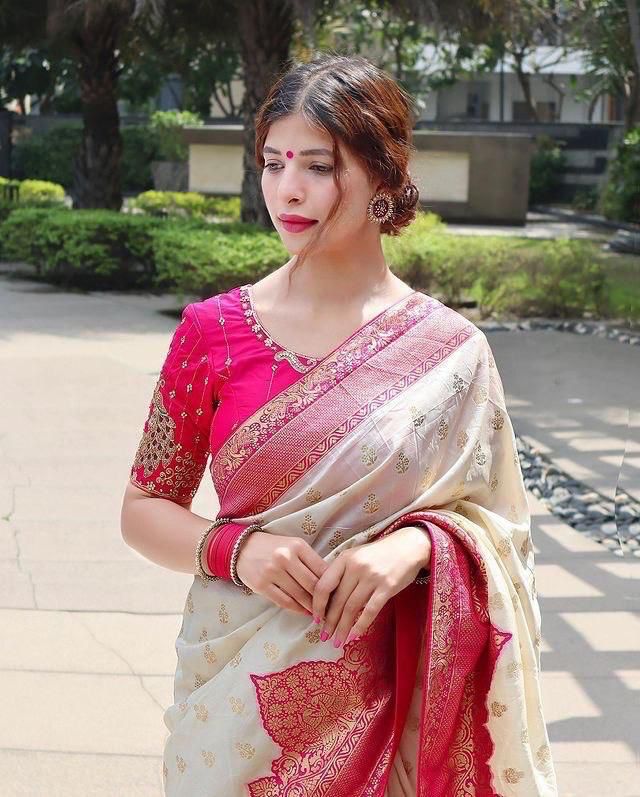 Woman posing in cream and pink Lichi silk saree with embroidered blouse