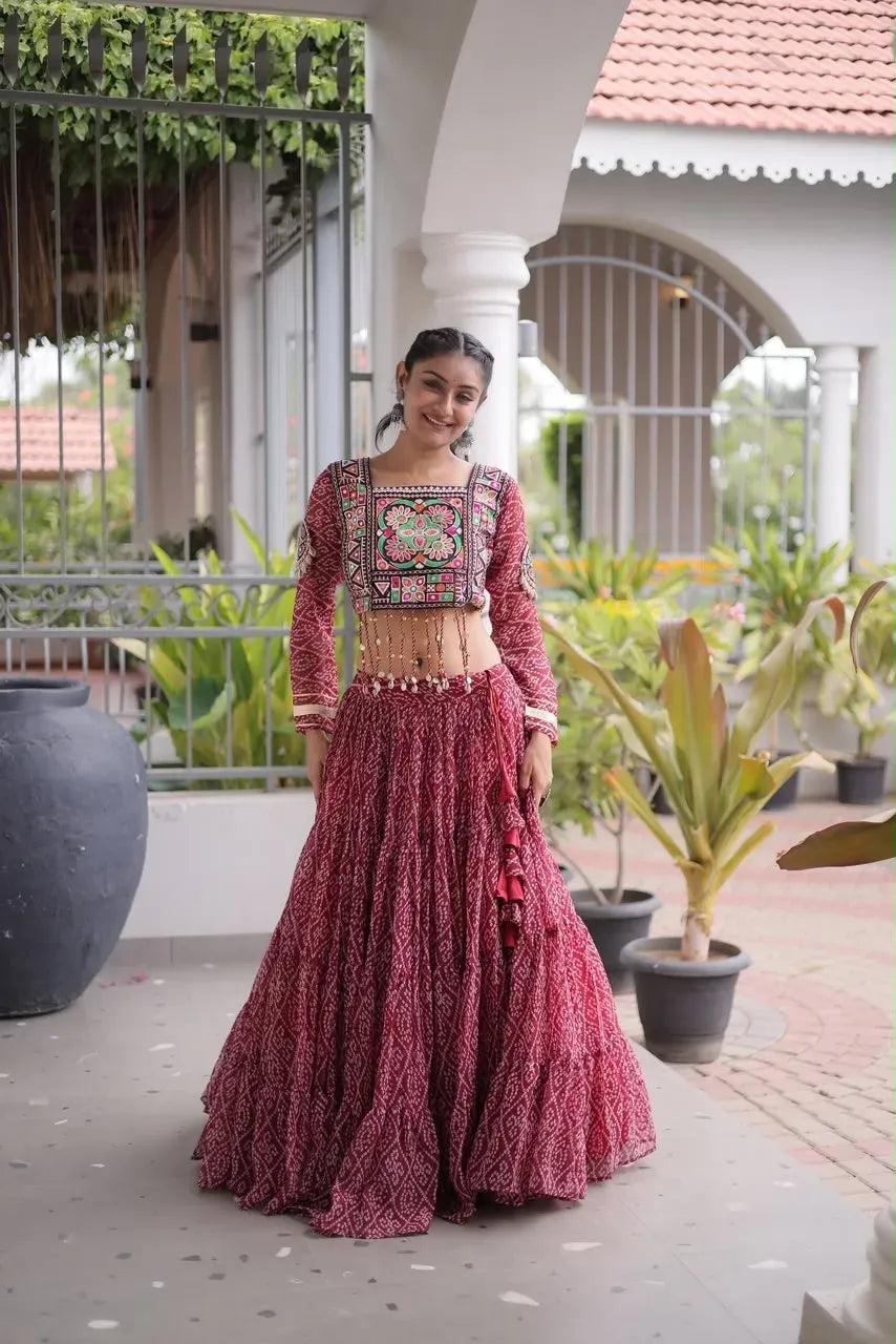 Woman in maroon georgette bandhani lehenga with designer square neck blouse standing outdoors