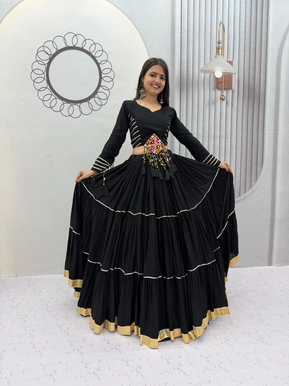Model holding out the massive nine-meter flare of the black cotton lehenga skirt smiling