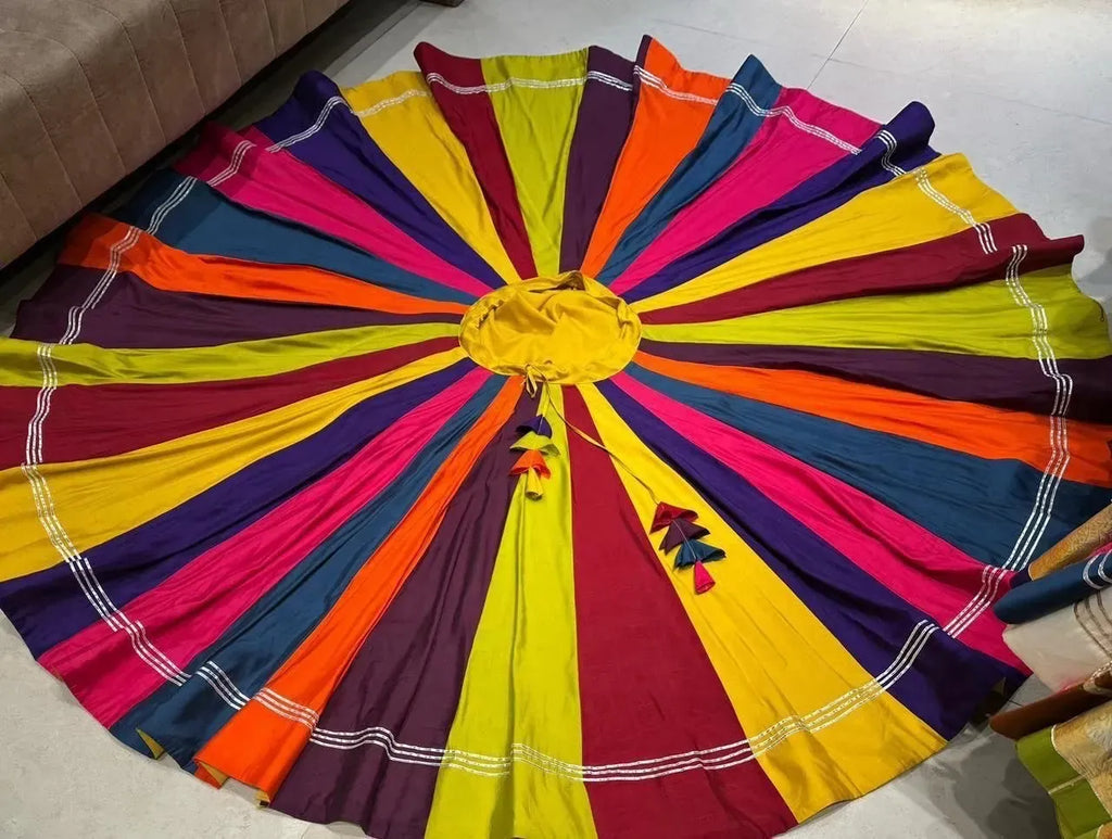 A vibrant multi color panelled flared chaniya skirt laid in a complete circle showing yellow waist tassels
