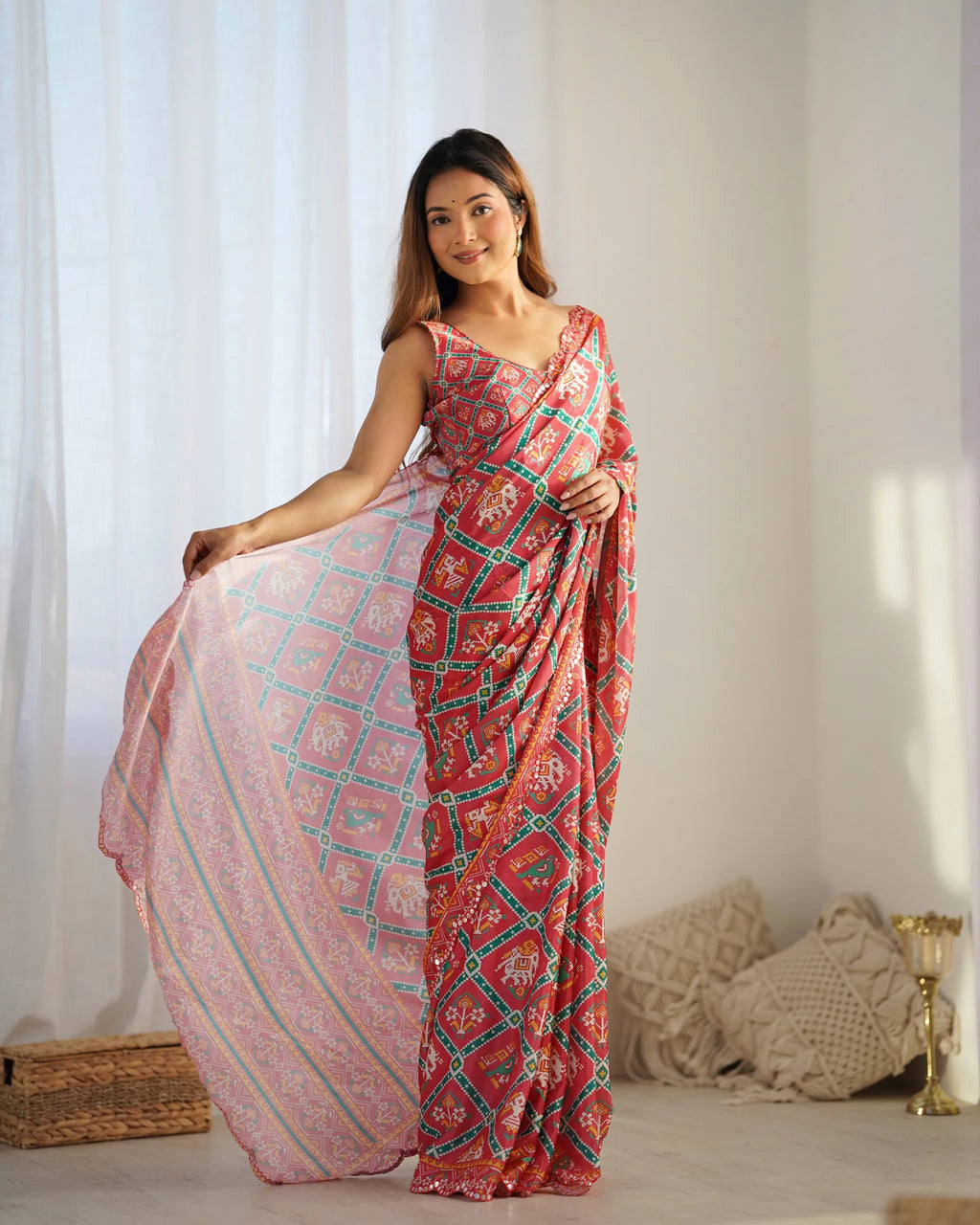 Model posing front-facing in heavy chinnon pink and red saree with mirror lace border