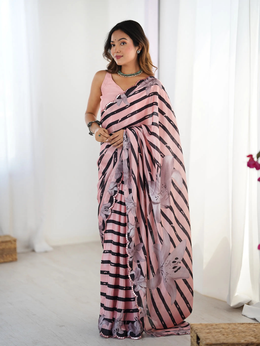 Model wearing pink chinnon saree with black stripes and floral print