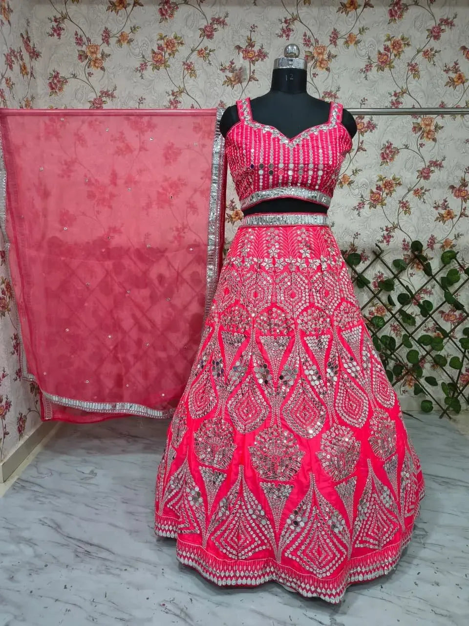 Designer pink Malai Satin lehenga choli displayed on a mannequin with floral wallpaper background