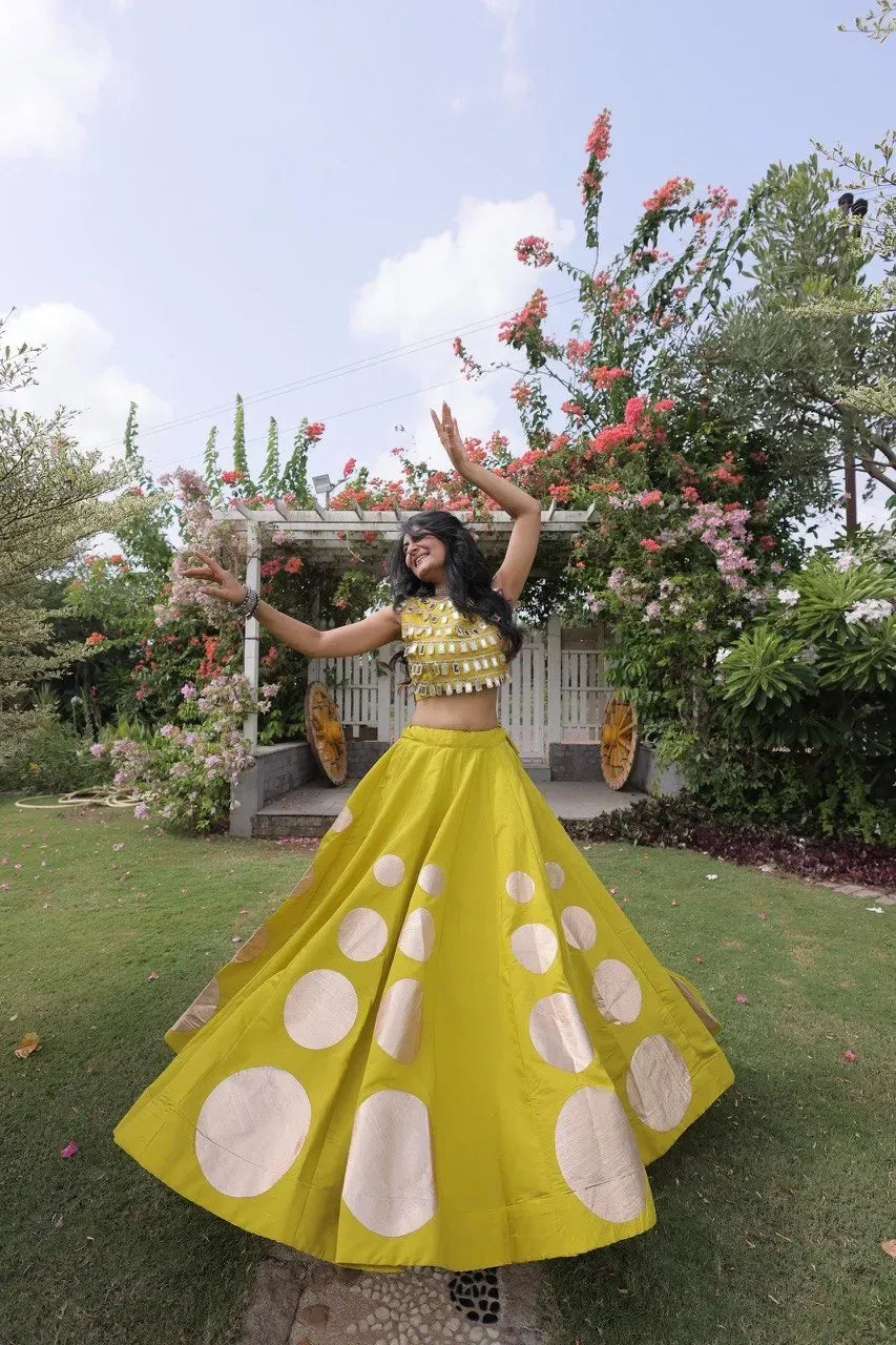 Model wearing yellow Roman silk lehenga with mirror work top outdoors
