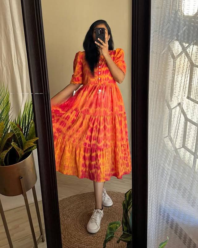 Woman in vibrant orange-red tie-dye midi dress, full length in mirror.