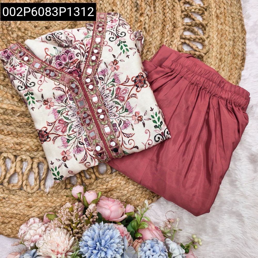 Traditional floral printed kurta top and rose pink sharara bottom set, folded on a rustic mat.